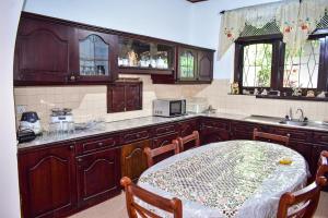a kitchen with wooden cabinets and a table in it at Wicks Backpacker's Lodge - Peaceful Quality stay, Walk to the Historic Galle Dutch Fort and the beach in Galle