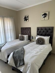 una camera con due letti con cuscini sopra di Aluz Guestunit, Self-catering a East London