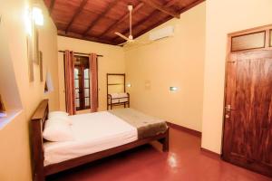 a bedroom with a bed and a wooden door at The House Dewata in Galle
