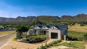 a house on a hill with mountains in the background at Klein River Cottage, Stanford Getaway in Stanford