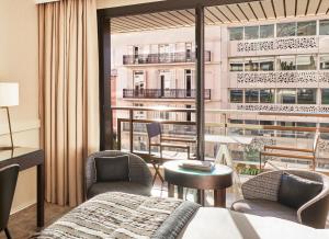 a hotel room with a bed and chairs and a balcony at Hôtel Barrière Le Gray d'Albion in Cannes