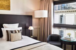 a bedroom with a bed and a chair and a window at Hôtel Barrière Le Gray d'Albion in Cannes