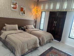 two beds in a room with windows at Alya Homestay Meulaboh in Meulaboh +4 photos