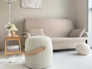 een witte poef in een woonkamer met een bank bij The Comfort in Seoul
