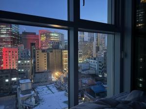 een raam met uitzicht op de skyline van de stad bij The Comfort in Seoul +28 foto's