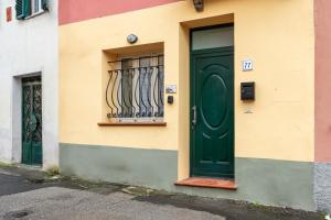 a green door on a building with a window at Casa Angeli - By The River in Lucca