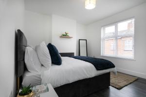 a bedroom with a bed with white sheets and blue pillows at The Modern Retreat in Leicester