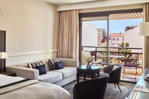 a hotel room with a bed and a couch and a table at Hôtel Barrière Le Gray d'Albion in Cannes