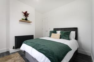 a bedroom with a large bed with green comforter at The Modern Retreat in Leicester
