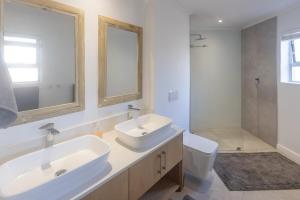a bathroom with two sinks and a toilet and a mirror at Simply Stunning but smaller in Cape St Francis +19 photos