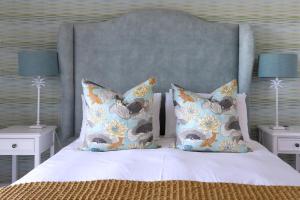 a bed with two pillows and two tables with lamps at Simply Stunning but smaller in Cape St Francis