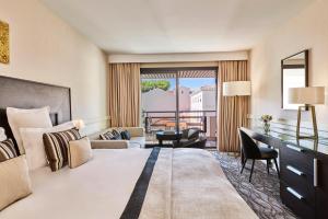 a hotel room with a bed and a balcony at Hôtel Barrière Le Gray d'Albion in Cannes