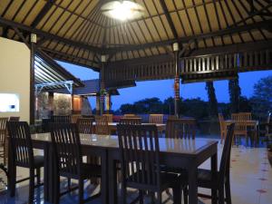 a restaurant with wooden tables and chairs under a roof at Antari Hotel Pemuteran in Pemuteran
