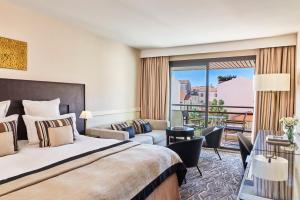 a hotel room with a bed and a balcony at Hôtel Barrière Le Gray d'Albion in Cannes
