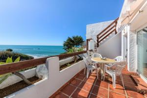 a balcony with a table and chairs and the ocean at Villas Flamenco Beach Conil in Conil de la Frontera