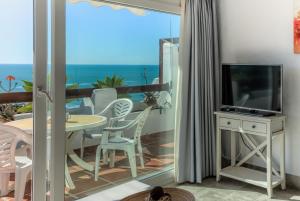 a room with a balcony with a television and a table at Villas Flamenco Beach Conil in Conil de la Frontera