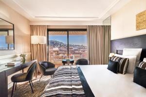 a hotel room with a king sized bed and a desk at Hôtel Barrière Le Gray d'Albion in Cannes
