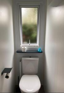 Un pequeño baño con inodoro y ventana. en Mobil Home Calina 4-6 personnes, en Litteau 2 fotos más