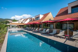 a swimming pool with chairs and umbrellas next to a house at James Vignoble Hôtel, Eguisheim in Eguisheim