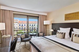 a hotel room with a bed and a balcony at Hôtel Barrière Le Gray d'Albion in Cannes