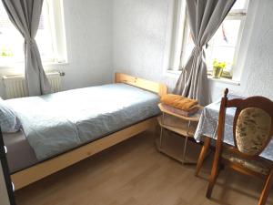 a bedroom with a bed and a chair and windows at Pension in Schwallungen