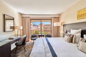 a hotel room with a bed and a desk and a window at Hôtel Barrière Le Gray d'Albion in Cannes