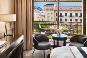 a hotel room with a bed and chairs and a large window at Hôtel Barrière Le Gray d'Albion in Cannes