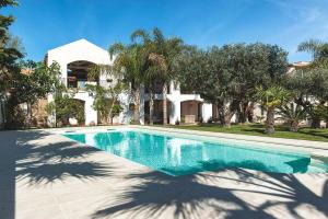 a swimming pool in front of a house with trees at Casa Marsala in Marsala