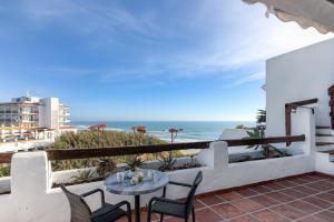a balcony with a table and chairs and the beach at Villas Flamenco Beach Conil in Conil de la Frontera