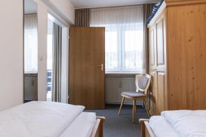 een slaapkamer met twee bedden en een stoel en ramen bij Ferienwohnung Richter in Oberstdorf