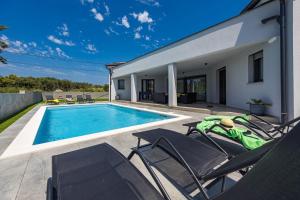 a villa with a swimming pool and two lawn chairs at Villa Speranza with Illuminated Pool in Pula