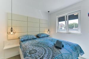 een slaapkamer met een bed met een blauw dekbed en een raam bij Villa DIV with pool in Bibinje +110 foto's