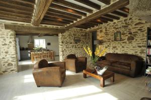 a living room with leather furniture and a stone wall at La petite vallée in Saint-Calais-du-Désert