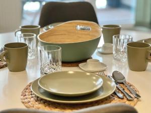 a table with a bowl and plates and glasses on it at Apartment Bergliebe, TV, W-Lan, Spülmaschine, Balkon in Siegsdorf +19 photos