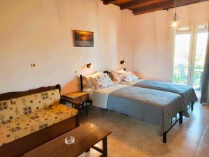 a bedroom with two beds and a couch in it at Kapases Studios & Apartments in Peroulades