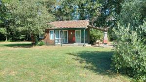 a small house with a red door in a yard at Chalet Aramis à la ferme in Pouylebon