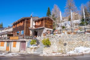 a large wooden building with a stone wall at Chalet Le Alpi - Azzurro Club in Prato Nevoso
