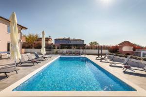 einen Pool mit Liegestühlen und Stühlen in der Unterkunft Villa Berg II in Valbandon