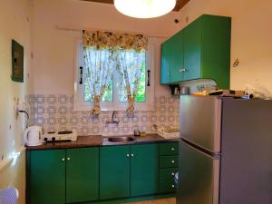 a kitchen with green cabinets and a refrigerator at Kapases Studios & Apartments in Peroulades