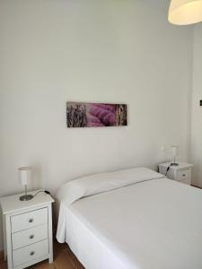 a white bedroom with a bed and a white nightstand at Apartamentos Fariñas 11 in Sanlúcar de Barrameda