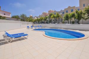 a swimming pool with lounge chairs next to a building at Almond Apartment by OCvillas in Vale de Pedras
