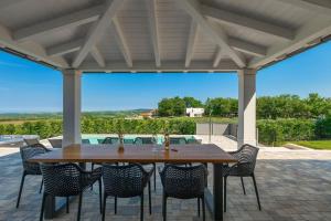een houten tafel en stoelen op een terras bij Luxury villa Arman with whirlpool in Visinada in Vranje Selo