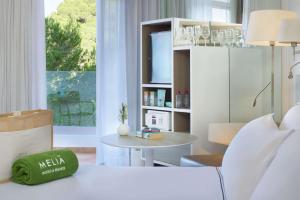 a bedroom with a bed and a table and a tv at Meliá Cala Galdana in Cala Galdana