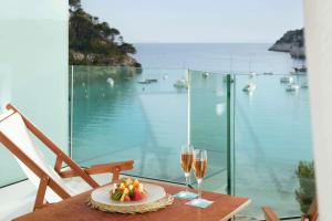 a table with two glasses of wine and a plate of fruit at Meliá Cala Galdana in Cala Galdana