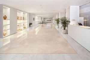an empty hallway with white walls and floors and plants at Melia Lebreros in Seville +124 photos