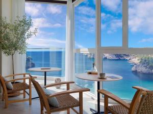 a room with tables and chairs and a view of the ocean at Meliá Cala Galdana in Cala Galdana