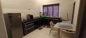 Una cocina con refrigerador y una mesa con sillas. en Homestay Bilal, en Kuantan