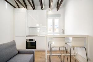 a living room with a couch and a kitchen with white cabinets at apartamentos en la avda de la albufera ALQUILER TEMPORAL in Madrid