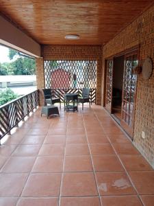 un porche cubierto con mesa y sillas en SNORING INN Mtubatuba, en Mtubatuba
