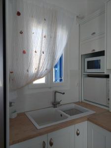 a white kitchen with a sink and a window at Harmonia Beach House in Kimolos